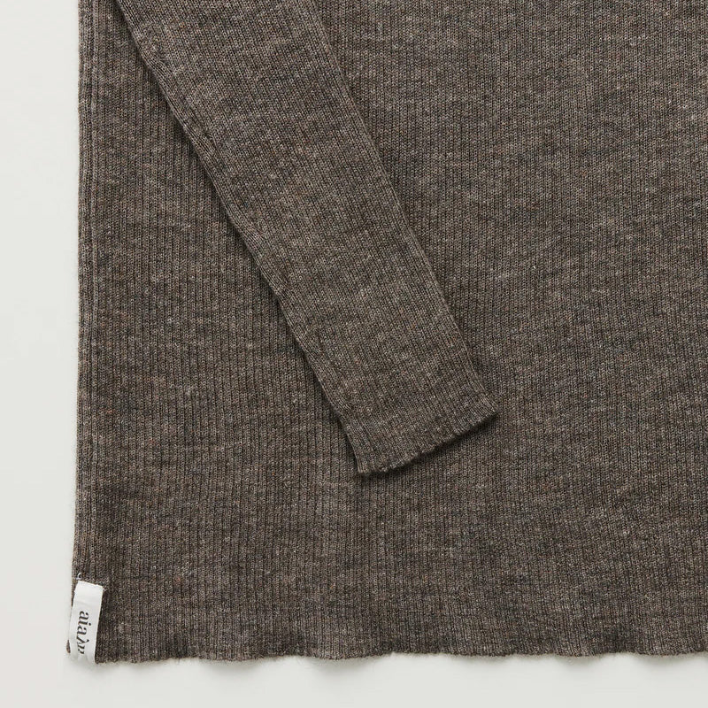 The Madigan Ribbed Cashmere LS by Aiayu is a luxurious brown sweater, boasting a distinctive ribbed texture, a visible sleeve detail, and a subtle label on the hem.