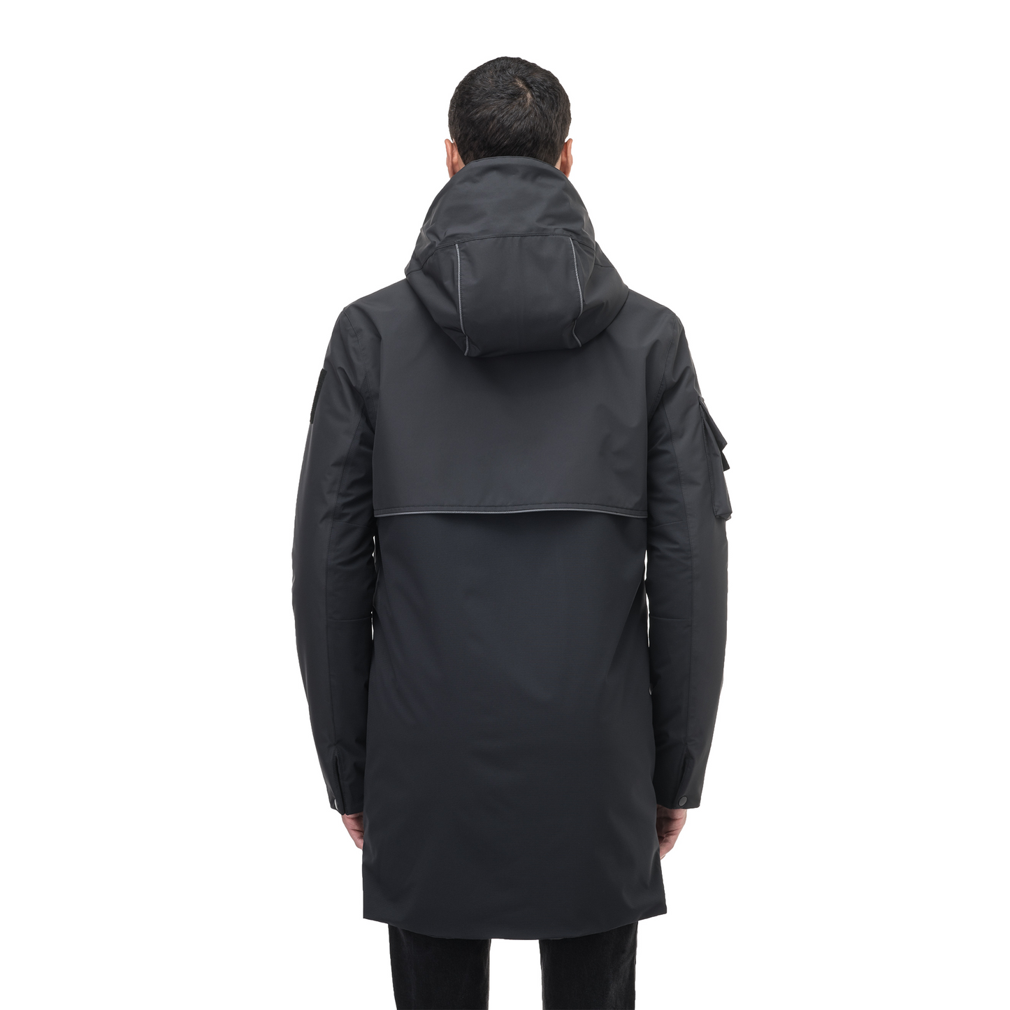 A person stands facing away, wearing a Nobis Alta Men's Performance Shell Jacket. This dark, hooded jacket with a high collar features PrimaLoft Gold Insulation to keep them warm.