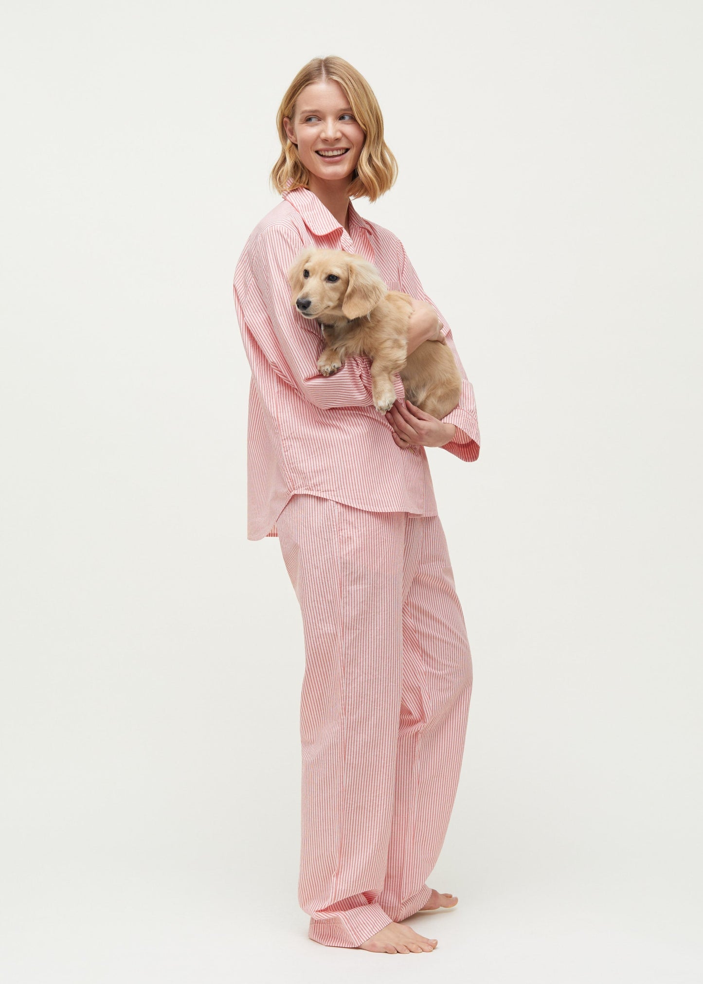 A person in the Pajama Night Petite by Aiayu holds a small dog while smiling.