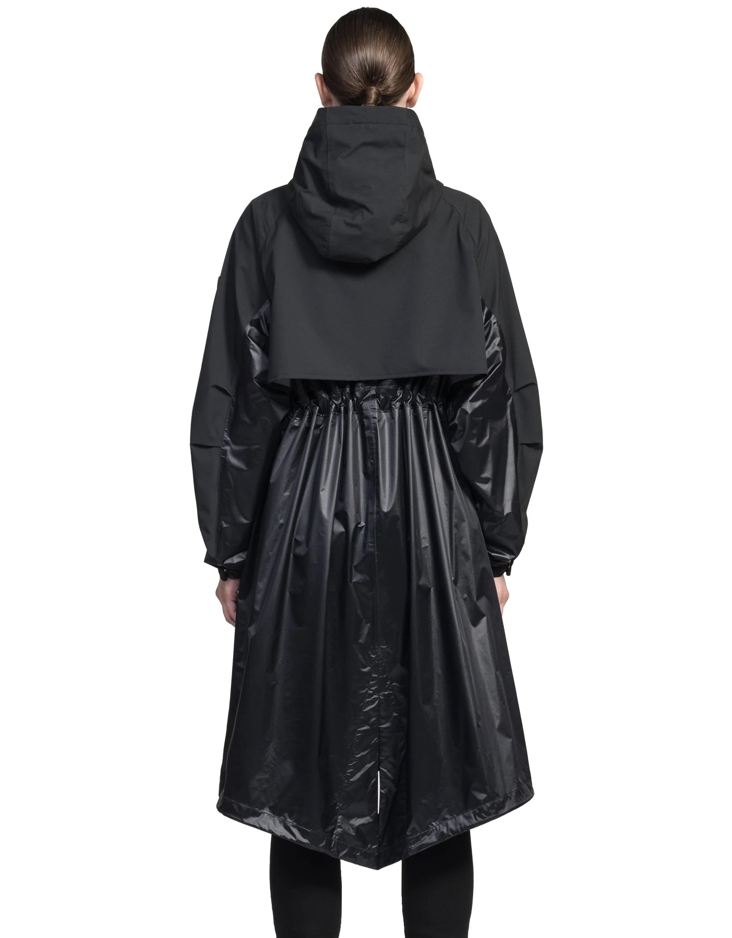 A person is seen from the back wearing the Reyna Women's Packable Long Shell Jacket in black by Nobis, featuring a hood and adjustable drawcords at the cinched waist for a perfect fit.