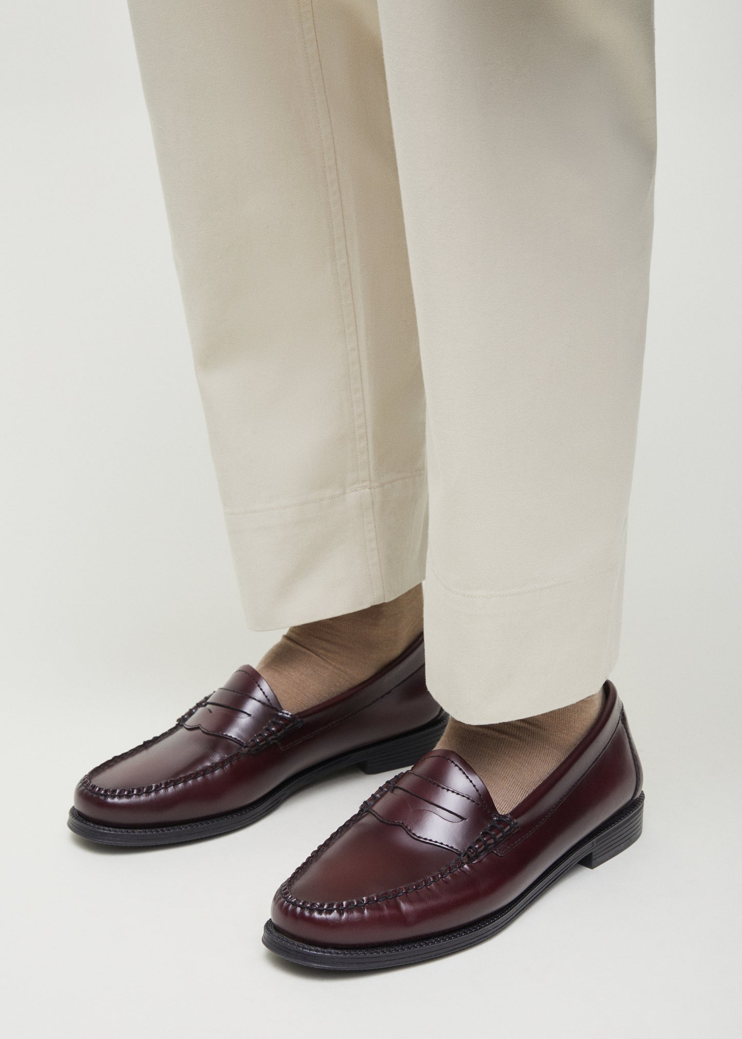 A person wearing beige pants, brown leather loafers, and luxurious Aiayu silk socks stands on a light background.