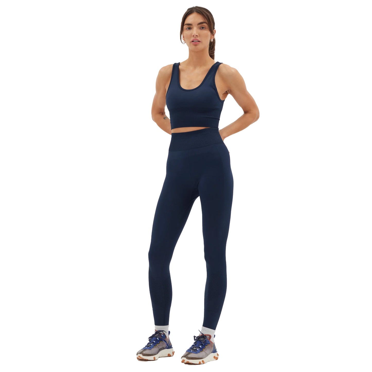 A person wearing the navy Sophia Legging from Halfdays, paired with sneakers, stands against a white background, poised for an outdoor adventure.