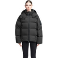 A person models the Nobis Una Women's Performance Puffer, a black waterproof jacket with a high collar, paired with black leggings against a plain white background.