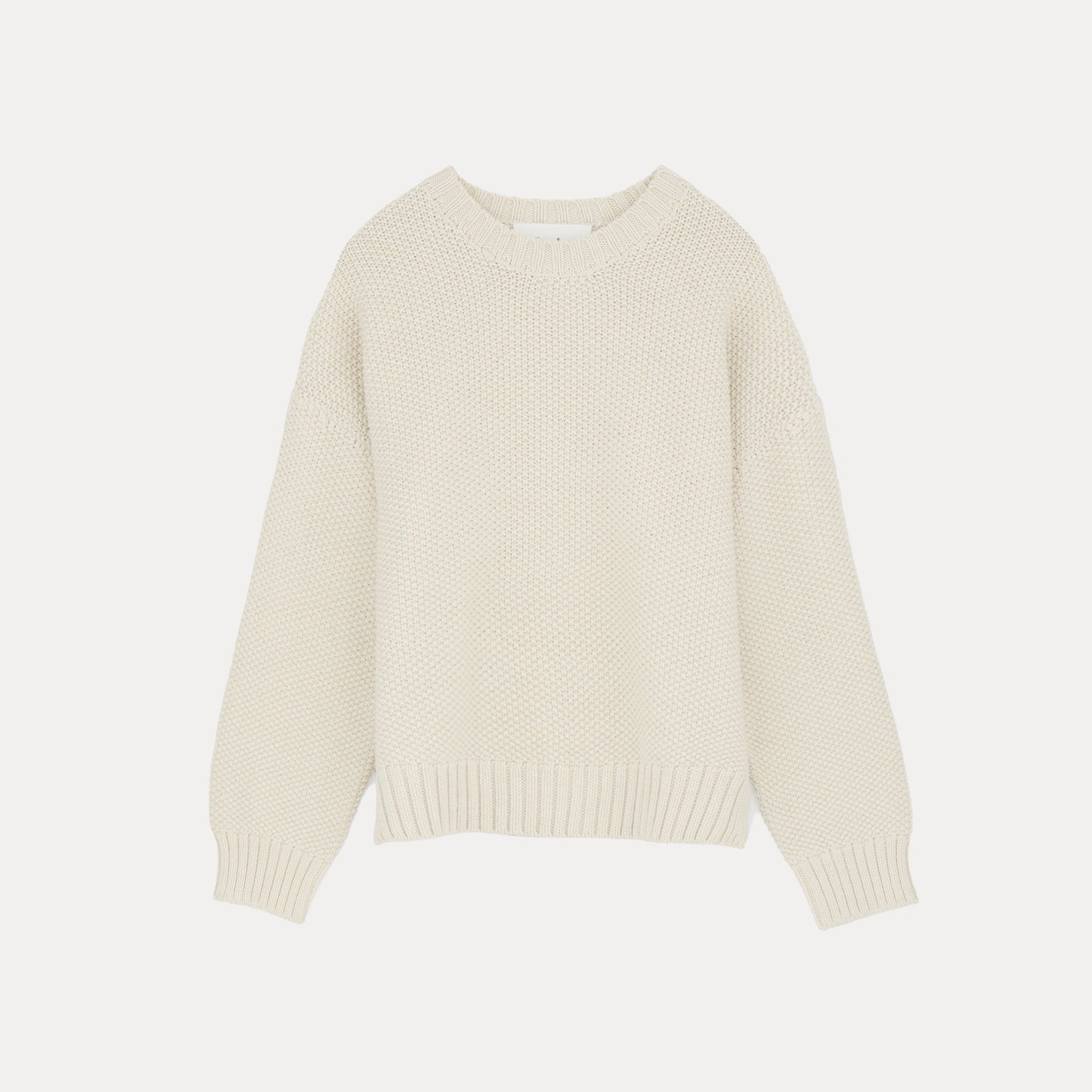 The Vetla Sweater by Aiayu is a luxurious cream-colored knit garment made from Highland Wool, featuring a round neckline and long sleeves, set against a white backdrop.