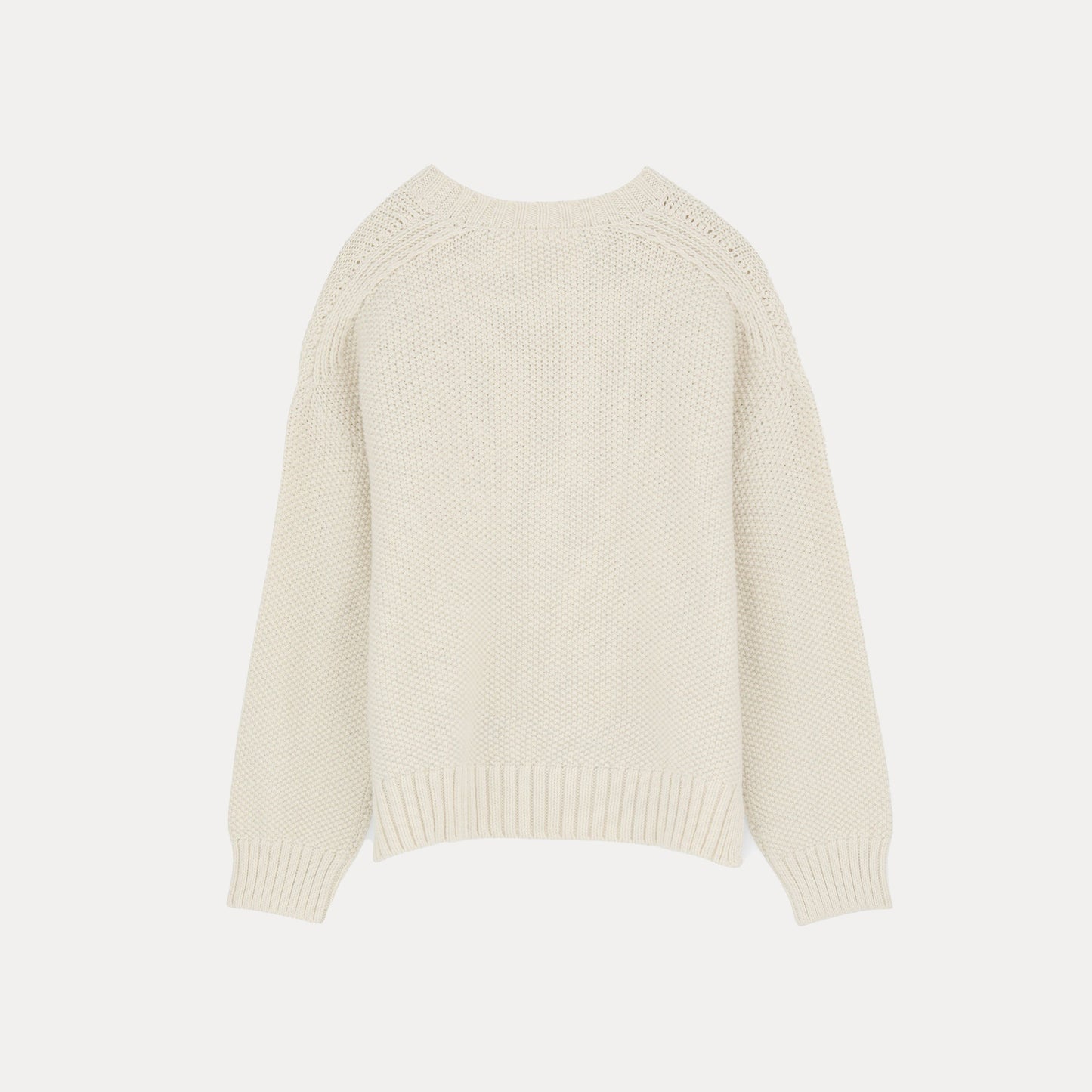 The Vetla Sweater by Aiayu, a cream-colored knit made from soft Highland Wool, features ribbed cuffs and hem and is laid flat against a white background.