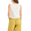 A person is shown from the back wearing Dockers Women's Sweater Tank in a crisp white, paired with vibrant yellow pants.