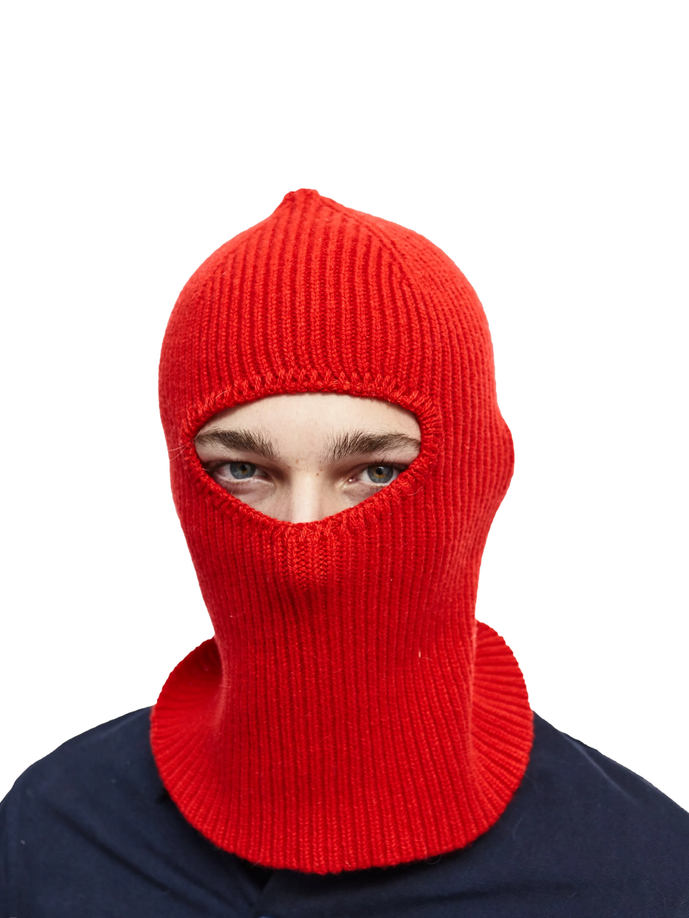 A person wears a red knit balaclava from Le Bonnet, made of luxurious cashmere, with only their eyes visible against a black background.