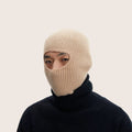 A person wearing an exclusive Le Bonnet beige ribbed balaclava made from luxurious Merino wool and a sleek black turtleneck, set against a neutral background.