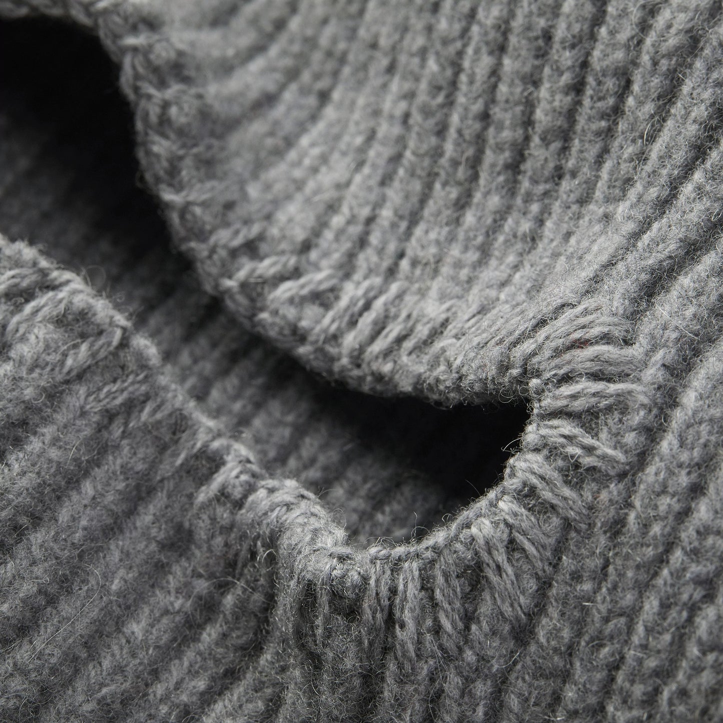 Close-up of a gray ribbed knitted fabric from the Le Bonnet balaclava, crafted in cashmere with detailed texture and fibers visible, showing a slight curve or fold in the material.