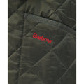 Close-up of a quilted fabric showing a pocket with the brand name "Barbour" embroidered in red. The Barbour B Liddesdale Quilted Jacket for boys is dark green with diamond-shaped stitching and features a needlecord collar, perfectly designed for kids sizing.