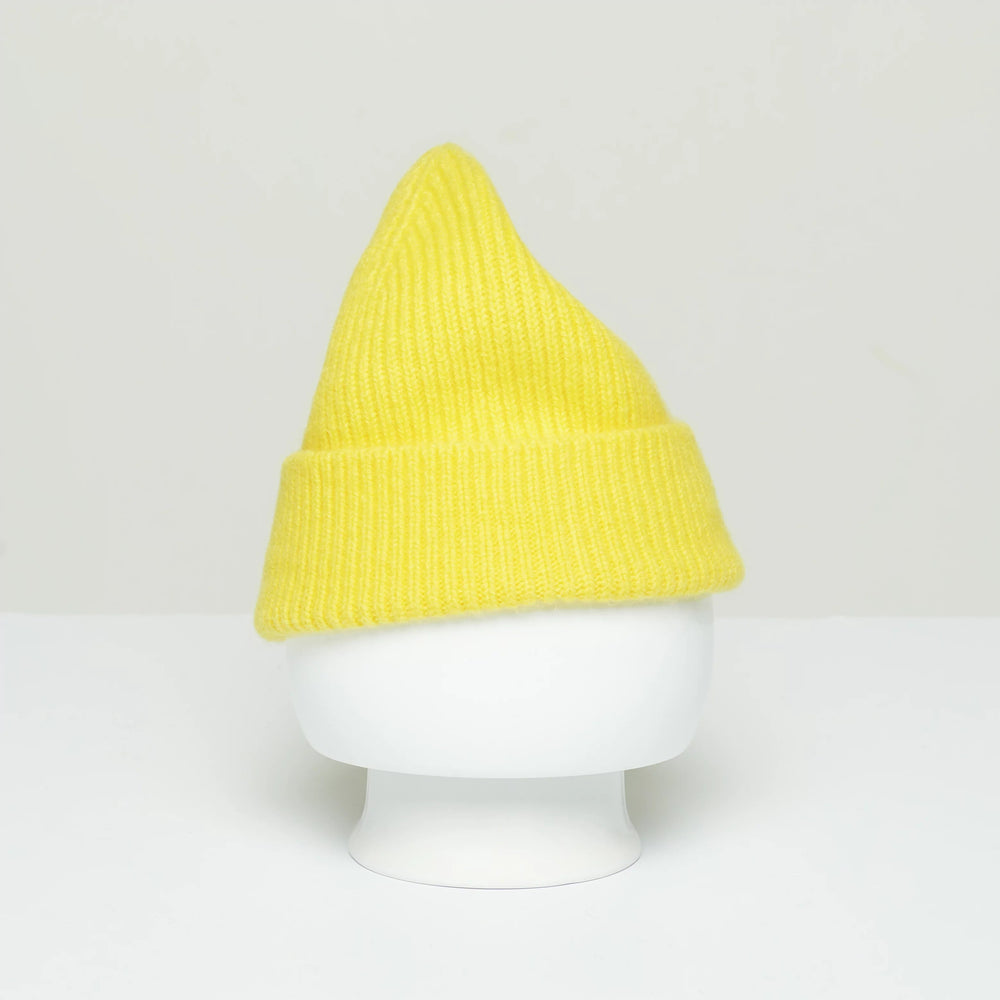 A Le Bonnet yellow woolen Beanie with a pointed top, inspired by traditional Scottish designs, is showcased on a plain white mannequin head against a neutral background.