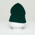 A green wool Beanie from Le Bonnet sits snugly on a white mannequin head, displayed against a plain background, evoking the craftsmanship of Scotland.