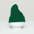 The Le Bonnet Beanie, made from the softest wool in a ribbed green design and crafted in Scotland, is showcased on a white mannequin head against a neutral backdrop.