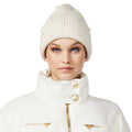 A person wearing the Goldbergh Hope Beanie in cream with small pearls, paired with a matching puffy white jacket, looks directly at the camera.