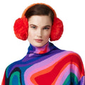 Person wearing orange fluffy ear warmers from Goldbergh and a colorful patterned sweater.