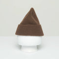 A ribbed beanie from Le Bonnet, crafted from the softest wool, this brown knit hat with a pointed top is manufactured in Scotland and displayed on a white mannequin head against a plain background.