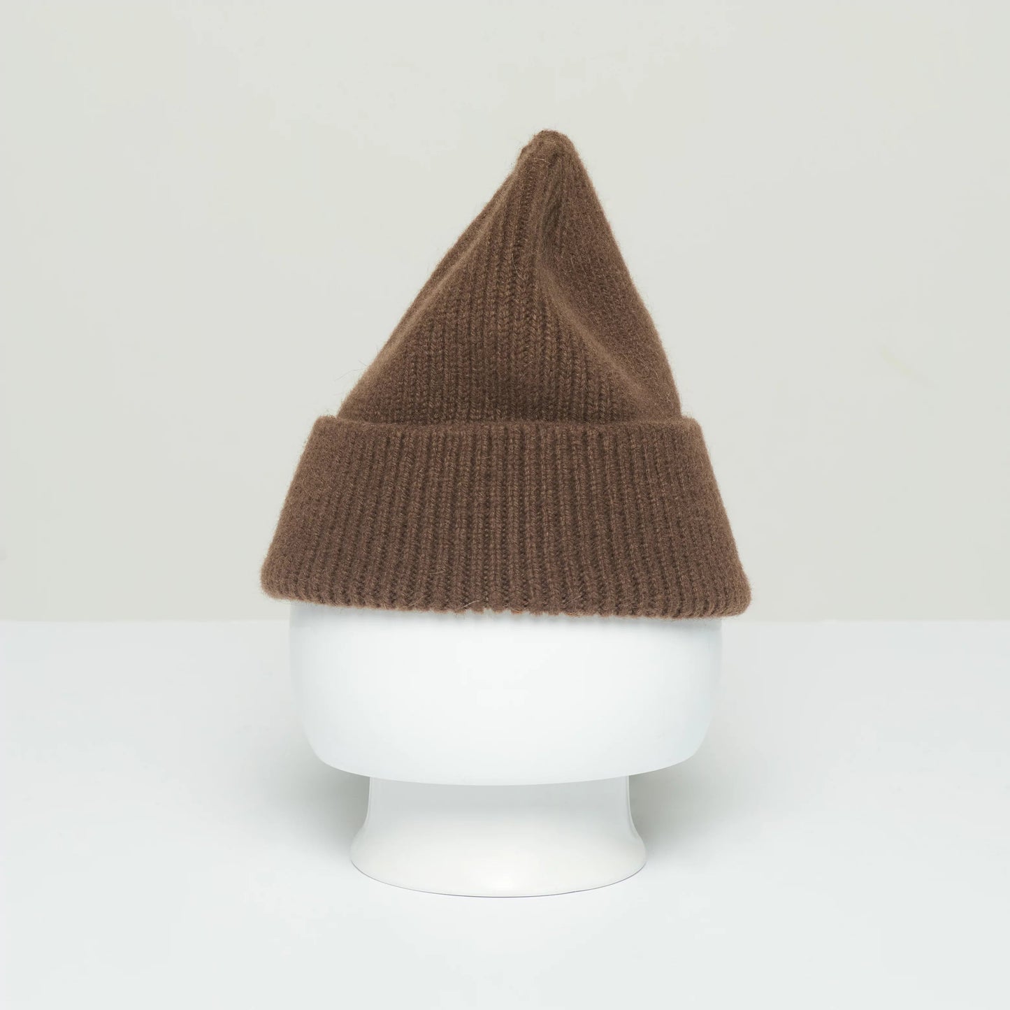 A ribbed beanie from Le Bonnet, crafted from the softest wool, this brown knit hat with a pointed top is manufactured in Scotland and displayed on a white mannequin head against a plain background.