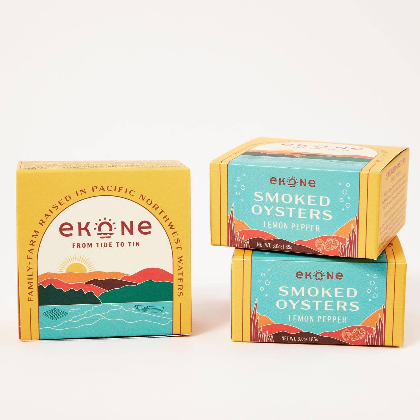 Three boxes of Ekone - Pantry Lemon Pepper Smoked Oysters, with one box standing upright and two stacked. The packaging features coastal imagery and text, highlighting the exquisite flavor of Willapa Bay oysters infused with lemon pepper spice.