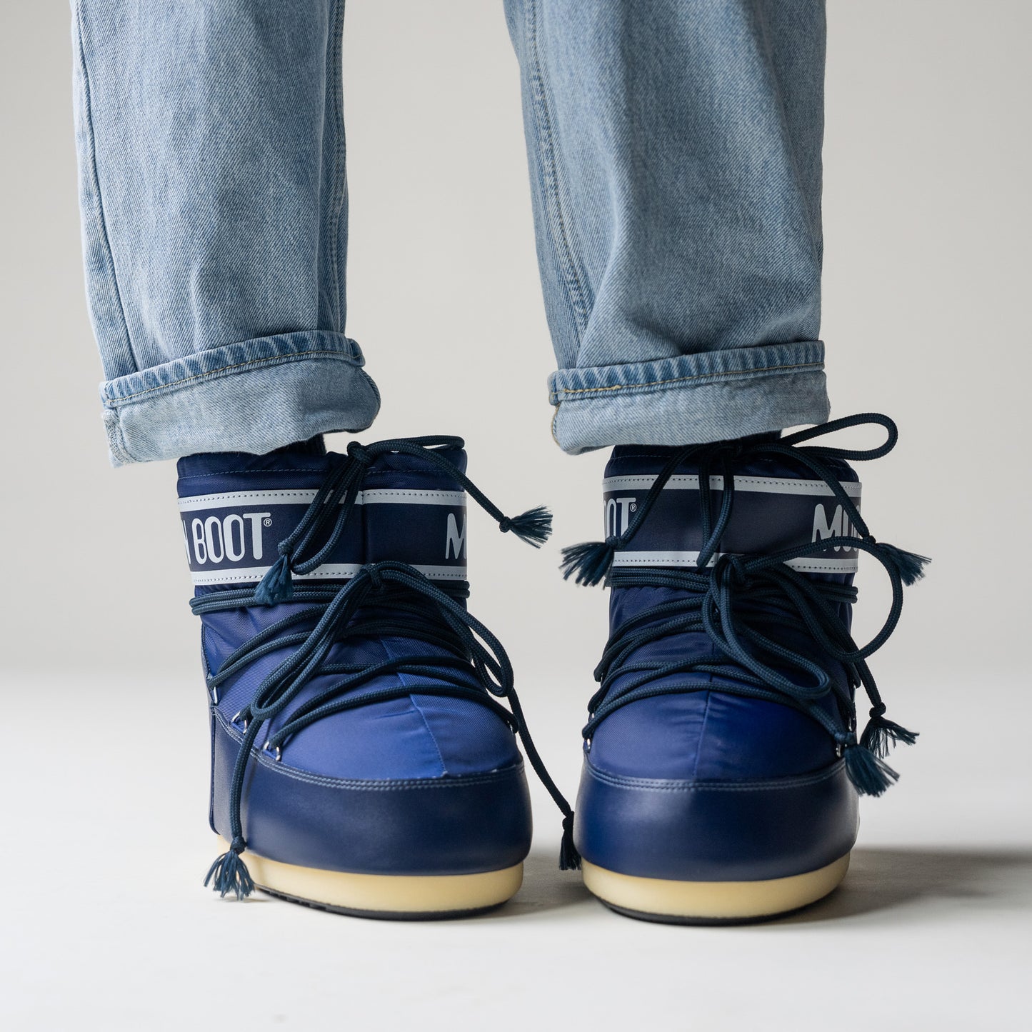 A person wearing the blue, water-repellent Moon Boot Icon Low Nylon shoes paired with light blue jeans.