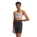 A person wearing the Flattering Sports Bra by Rohnisch, featuring a pattern and logo, pairs it with black high-waisted bike shorts while posing against a plain background.