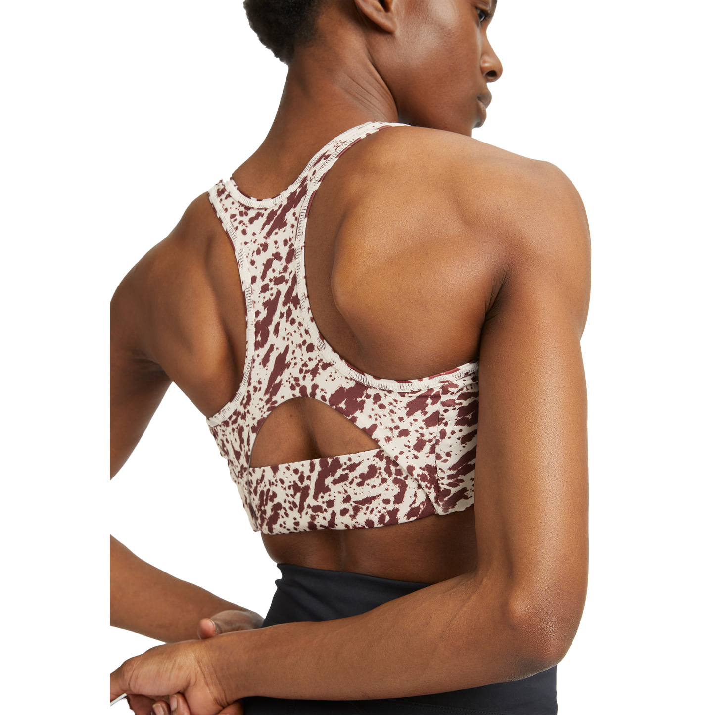 Clad in the Flattering Sports Bra by Rohnisch, which features a stylish pattern and racerback design, the person turns away to proudly showcase their toned back muscles and confidently crossed arms.