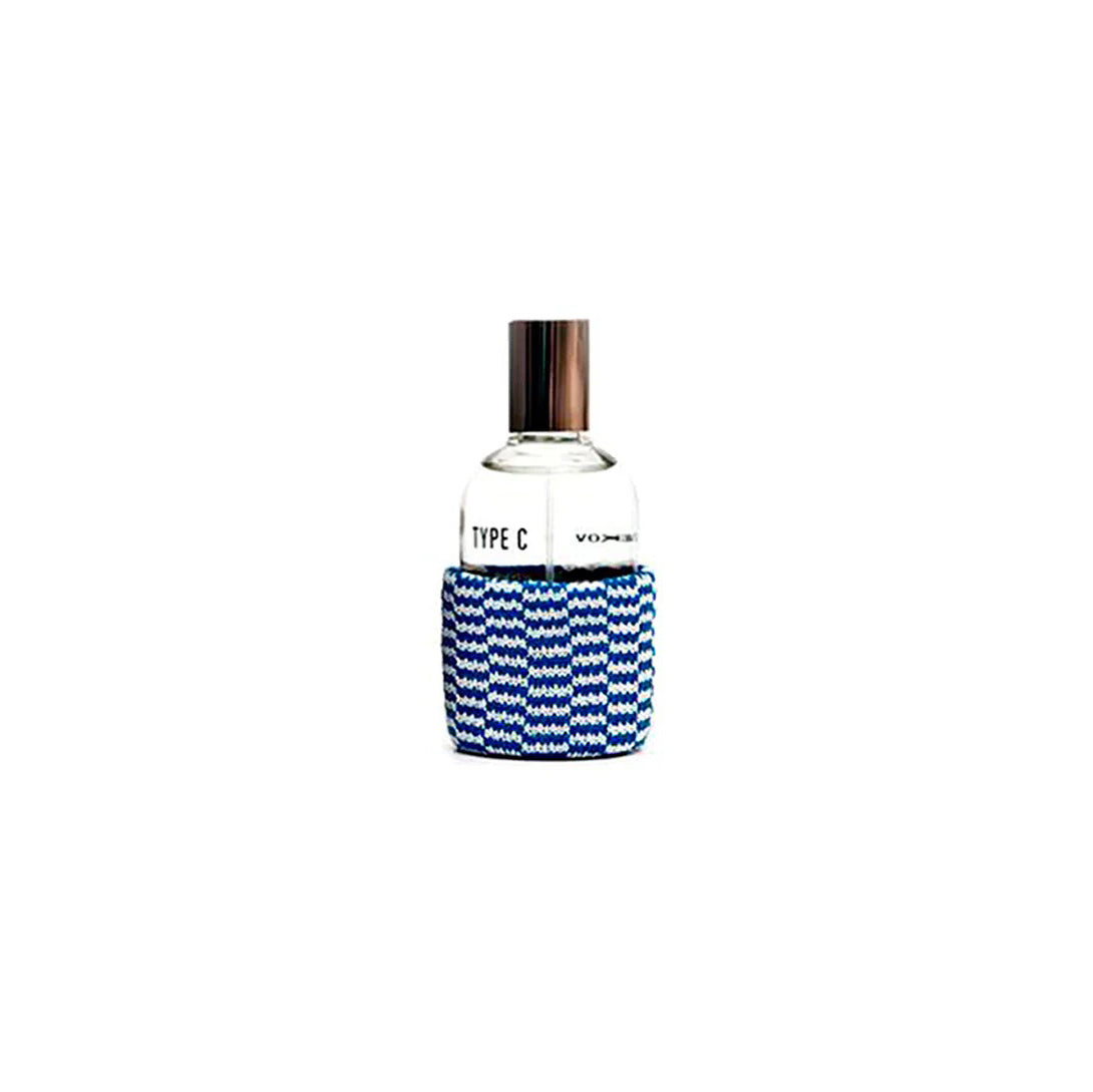 The Type-C Eau de Toilette by Henrik Vibskov features a silver cap and a blue-and-white patterned sleeve at the base, capturing the refreshing essence of a sea breeze.