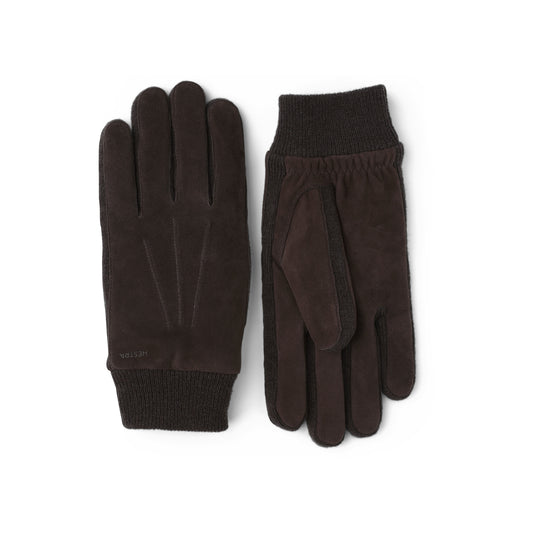 The Geoffrey Espresso gloves by Hestra are crafted from dark brown Italian lambskin suede with ribbed cuffs, shown with one glove facing up and the other down.