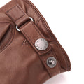 A close-up of the Nelson, Chestnut glove made of Italian lamb nappa leather from Hestra shows metal button details and stitching, with the brand name inscribed on one button.