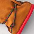 Close-up of the Hestra Wakayama boot in cork/brown cowhide with green and red shoelaces tied in a knot, featuring a red sole and visible stitching details.