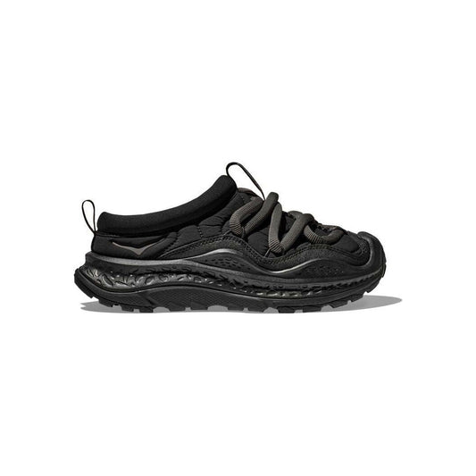 The U Ora Primo by Hoka boasts a black sneaker design with a textured sole, thick gray laces, a low collar, and an insulated puff upper. Perfect for recovery days, it offers easy slip-on functionality for added comfort.