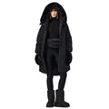 A person is pictured wearing the Julia Jacket by Goldbergh, which is a long black coat featuring a fur-lined hood. They are also dressed in black leggings, gloves, boots, and carrying a waist bag while standing against a white background.