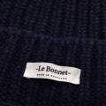 The label on Le Bonnet's "Logo Beanie, Midnight" indicates it is made in Scotland. This dark, knitted beanie offers timeless style and quality craftsmanship for warmth and comfort.