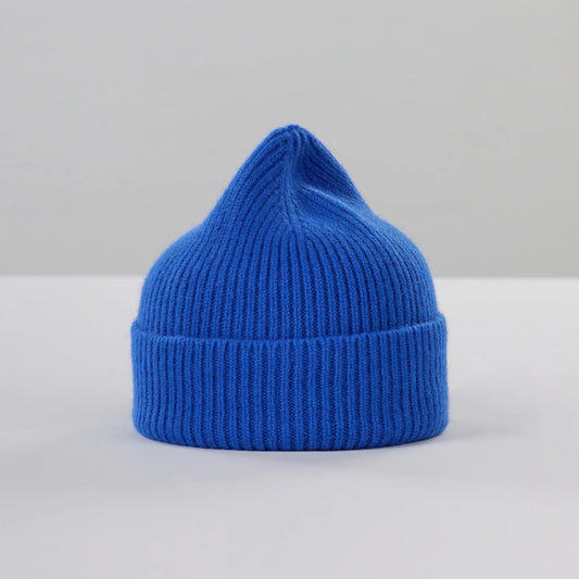 Le Bonnet's Royal Azure beanie, crafted from lambswool with a pointed top, is highlighted against a plain, light background.