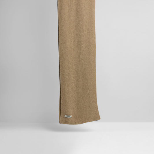 A long sand-colored Le Bonnet scarf, made of lambswool with a small label, is displayed vertically against a plain white background.