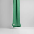 The Jade scarf from Le Bonnet drapes elegantly against a light gray backdrop, adding a refined touch to the scene.