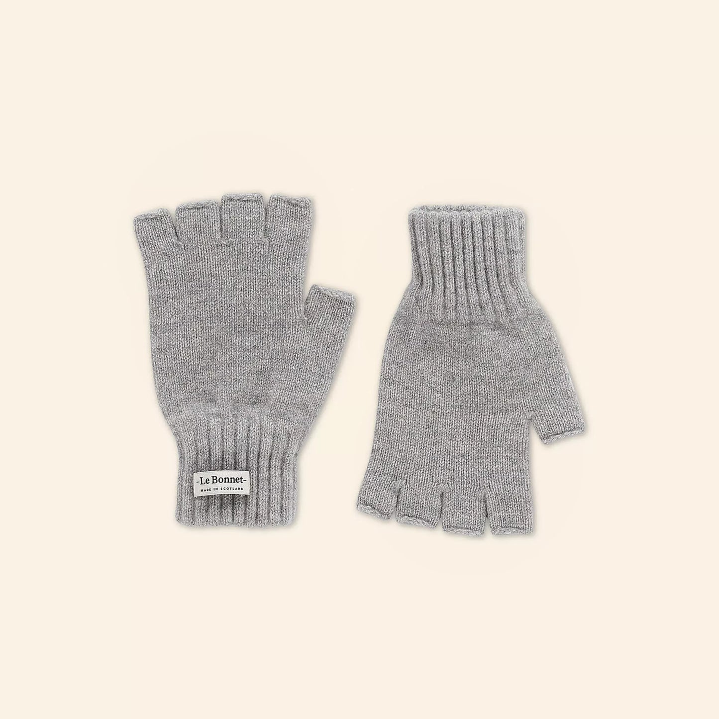 Smoky gray fingerless gloves with ribbed cuffs, made from Merino wool. A "Le Bonnet" label adorns one glove.