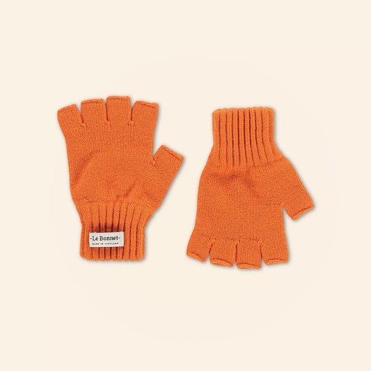 A pair of flame-colored fingerless gloves on a beige background showcases one palm and one back, crafted from soft Merino wool. Ideal for colder days, they feature a "Le Bonnet" label, highlighting the fine Scottish craftsmanship.