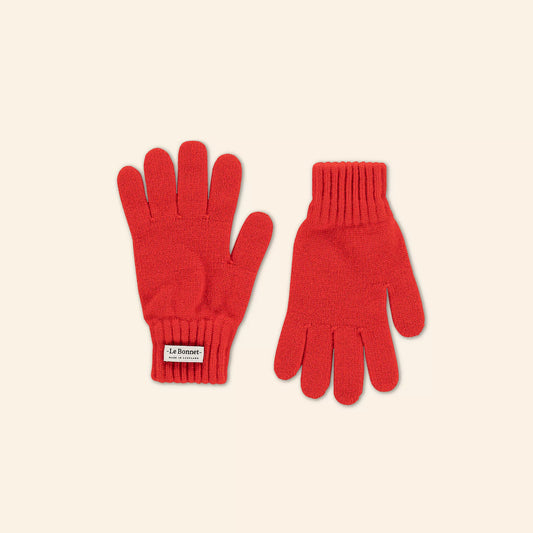 Displayed against a plain background, two crimson knit gloves, made from soft Merino Wool and featuring "Le Bonnet" branding, offer cozy warmth and a touch of Scottish elegance—perfect for colder days.