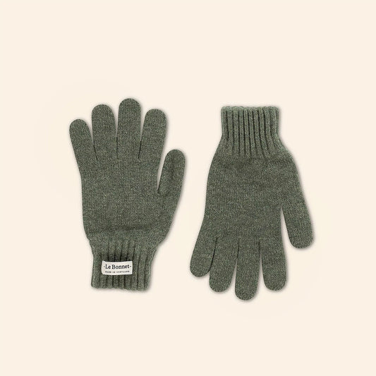 Two green knit gloves made from Merino wool by Le Bonnet rest on a plain background. Each Croco glove features a ribbed cuff, ideal for cold days, with one displaying a small label, reflecting craftsmanship fit to withstand Scotland's brisk breezes.