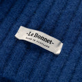 Close-up of a knitted lambswool scarf in blue featuring a white label that says "Le Bonnet - Made in Scotland.