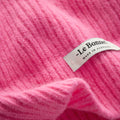 Close-up of a pink ribbed lambswool garment, likely a scarf, featuring a label: "Le Bonnet - Made in Scotland." Product: Scarves, Bubblegum.