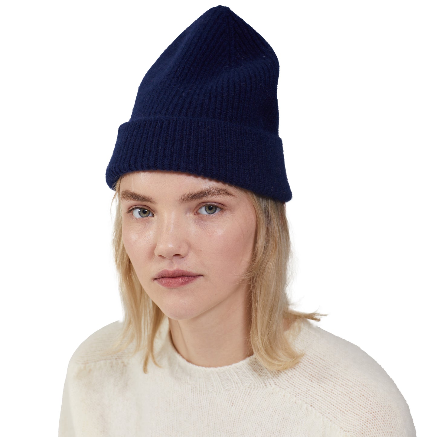 A person is wearing a dark blue Le Bonnet lambswool beanie and a white sweater against a plain background.