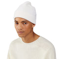 A person wearing a Le Bonnet white lambswool beanie and sweater against a plain background.