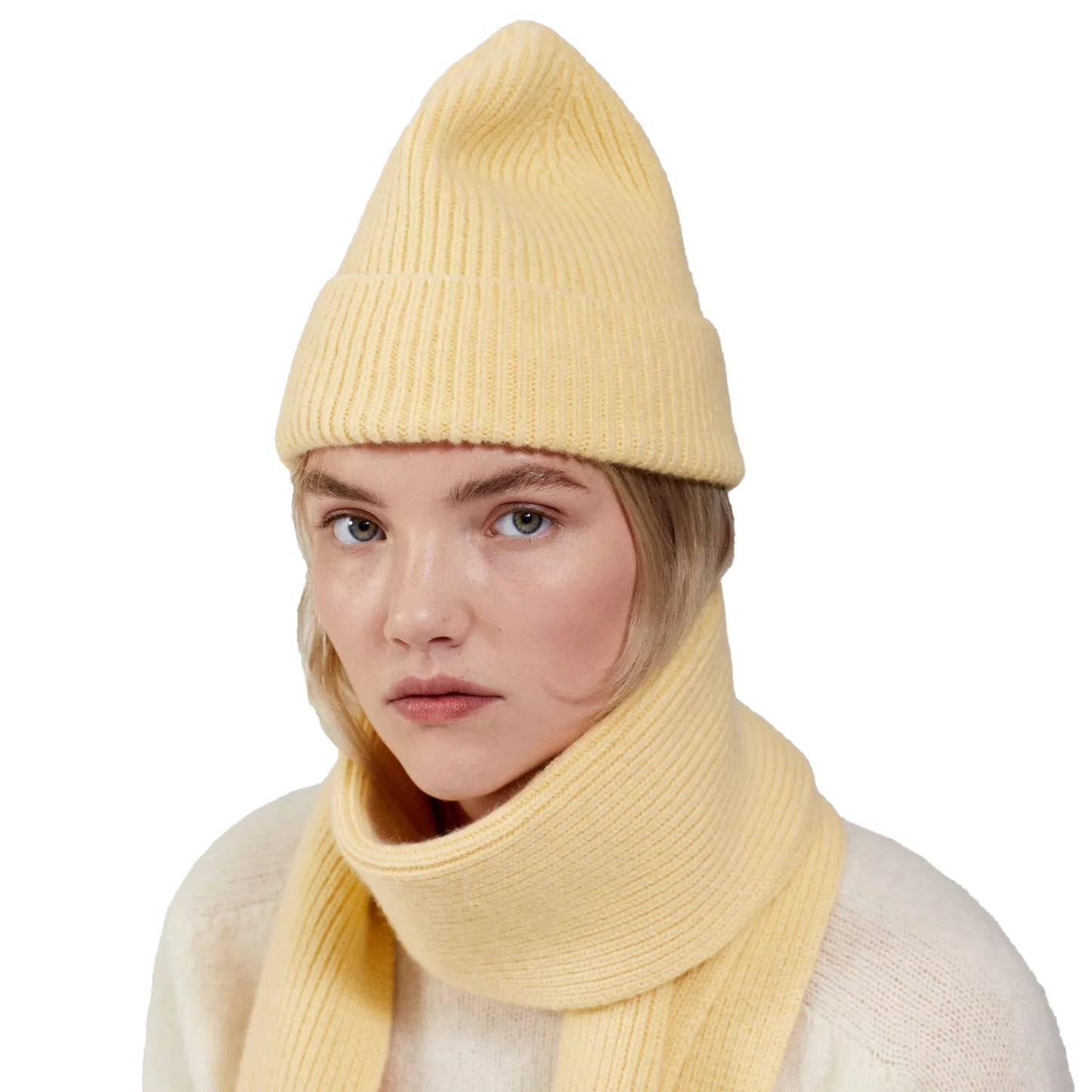 A person donning a light yellow Le Bonnet Beanie and matching scarf, with a neutral expression, set against a plain white background.