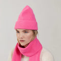 A person wears a bright Bubblegum lambswool knit hat and matching Le Bonnet scarf, facing slightly to the side with a neutral expression against a plain background.