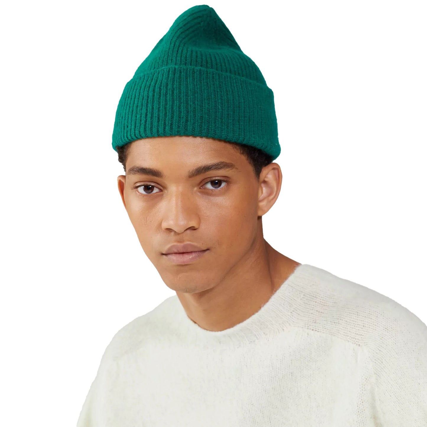 A person wearing a Le Bonnet Beanie in green and a light sweater looks directly at the camera against a plain background.