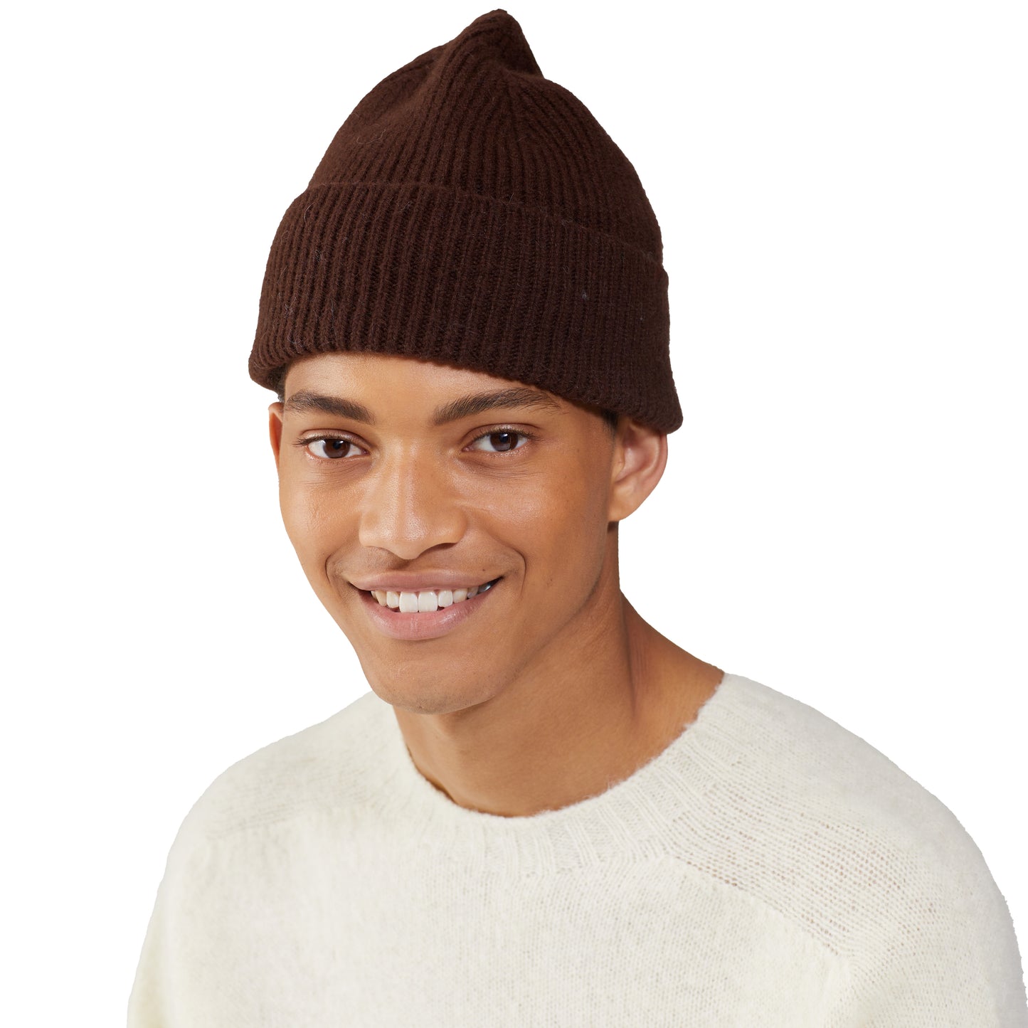 A person wearing a Le Bonnet brown lambswool beanie and a cream sweater smiles against a plain white background.