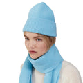 A person wears a blue Le Bonnet beanie and scarf with a neutral expression, dressed in a white sweater.