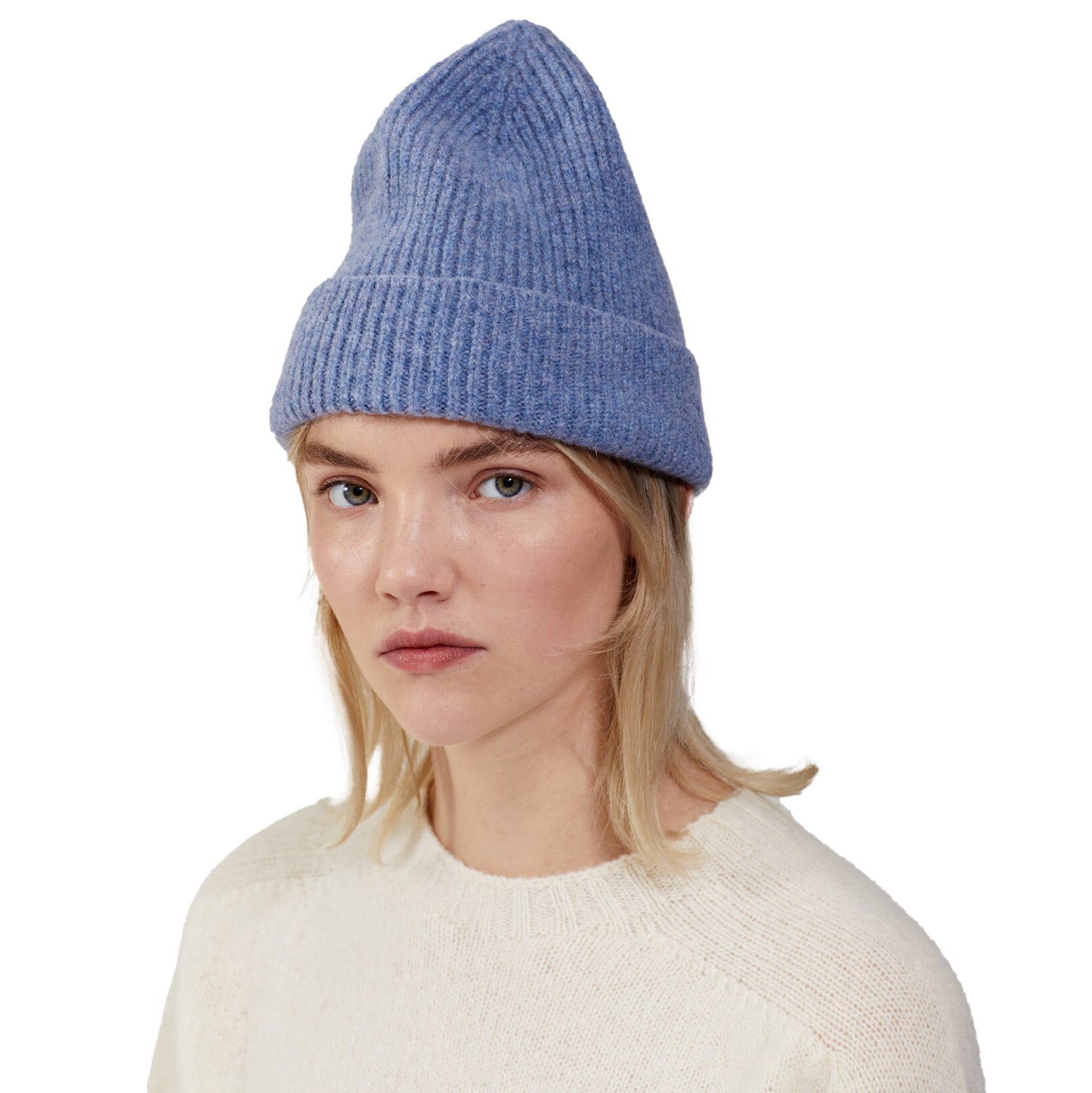 A person with blonde hair is shown wearing a blue Le Bonnet lambswool beanie and a cream sweater, looking directly at the camera against a plain white background.