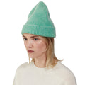 A person wearing a Le Bonnet light green beanie made from lambswool along with a white sweater.